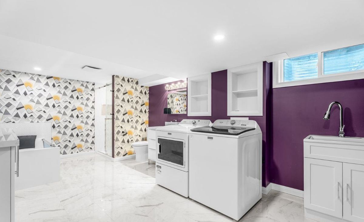 Basement laundry room with deep purple walls, white trim and a patterned wallpaper wall
