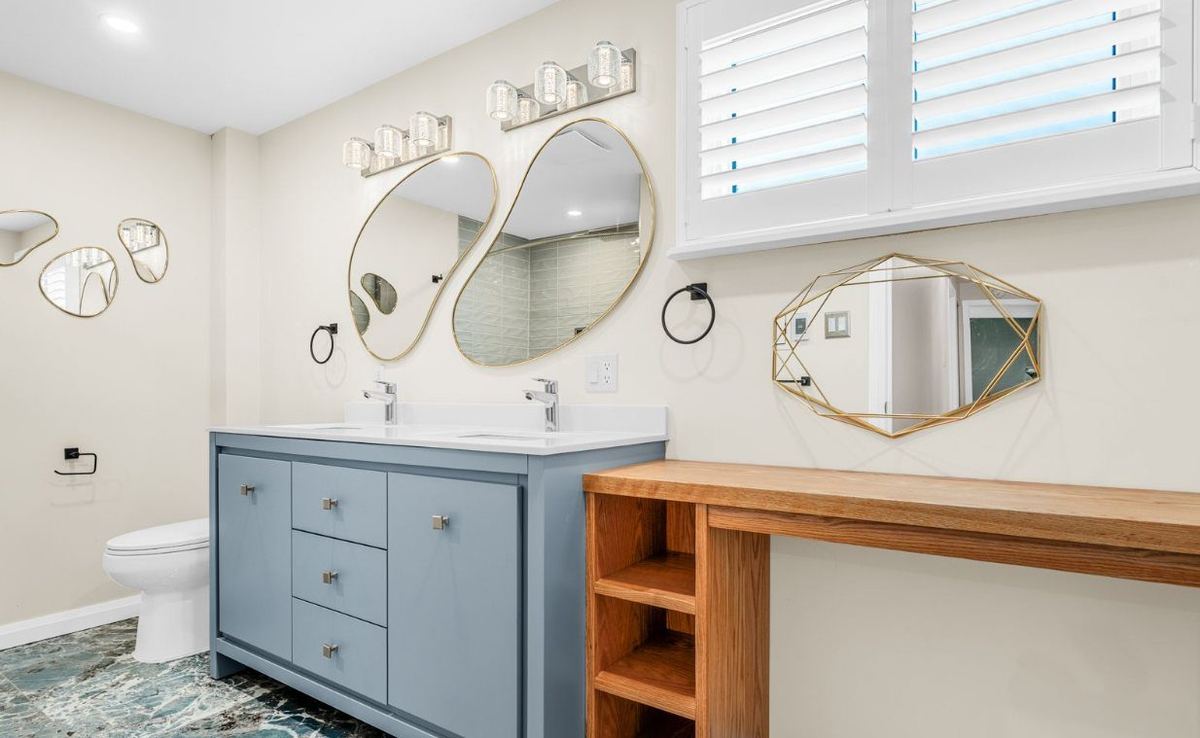 Bathroom with light walls, white shutters and a blue double vanity