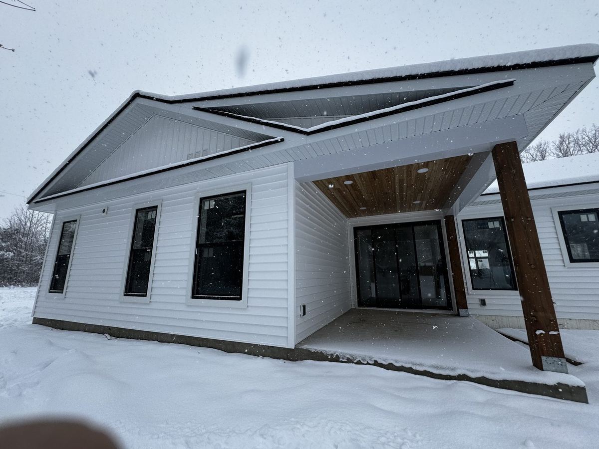White-sided home with a stained wood porch ceiling and a timber post