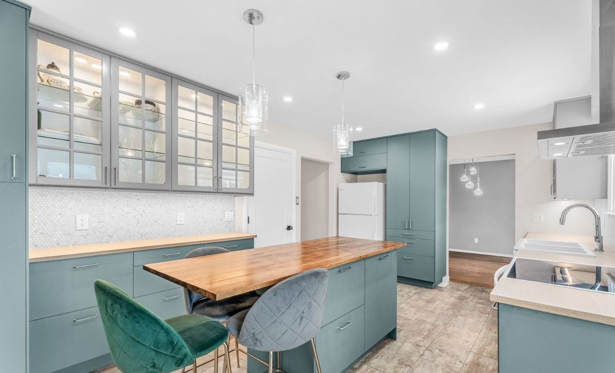 Kitchen with sage-green cabinets, glass-front uppers and light walls