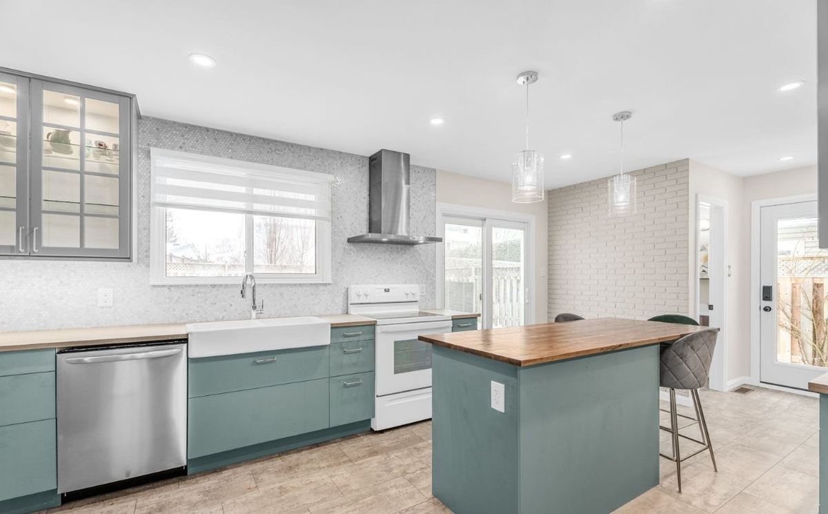 Kitchen with sage-green cabinets, light walls and a butcher-block island