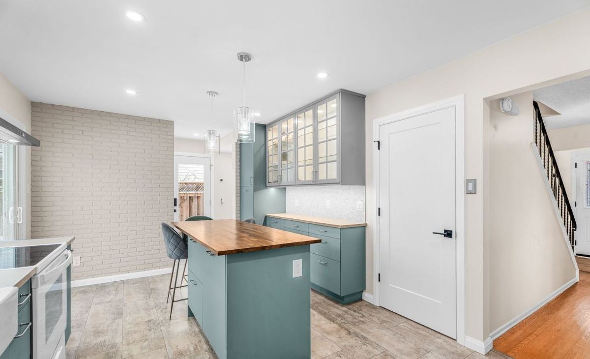 Kitchen with a painted white brick wall, light walls and a wood-top island