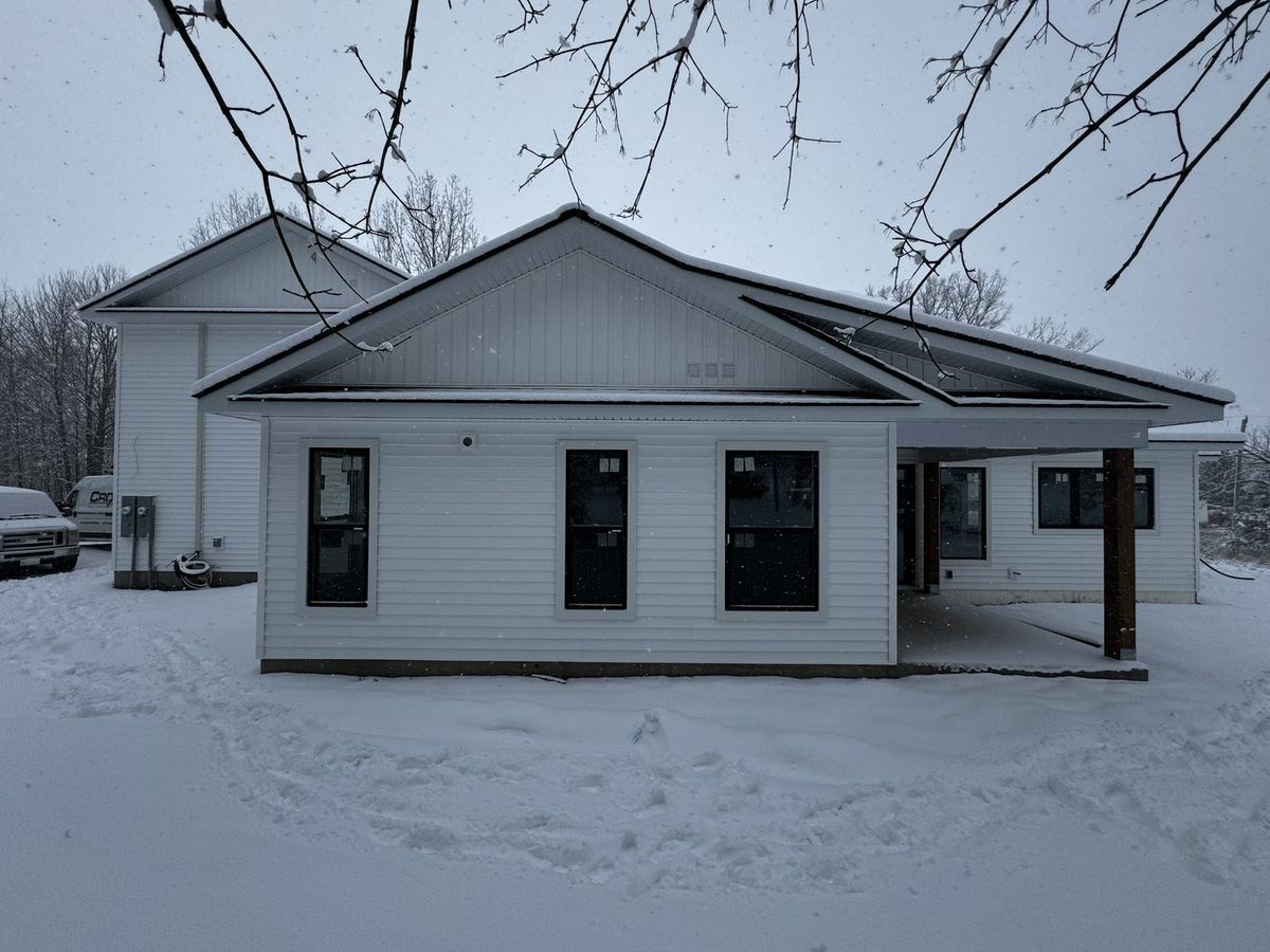Bungalow with white siding, black window frames and white trim in winter