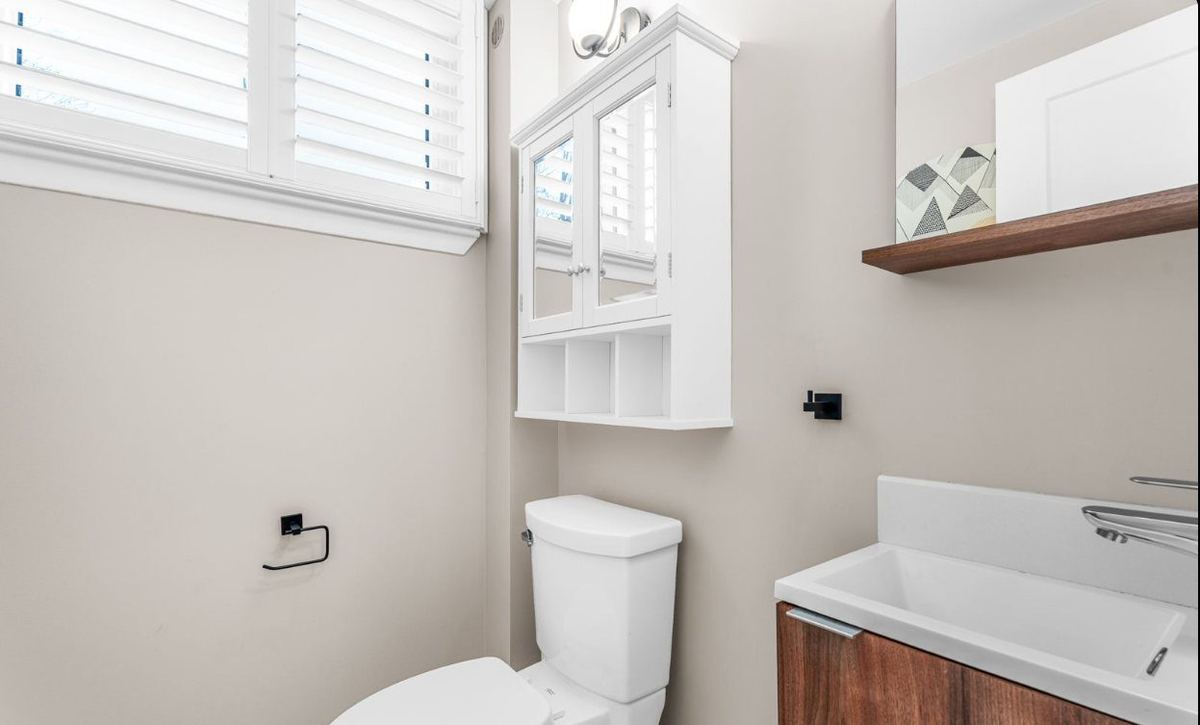 Powder room with soft beige walls, white trim and a walnut vanity
