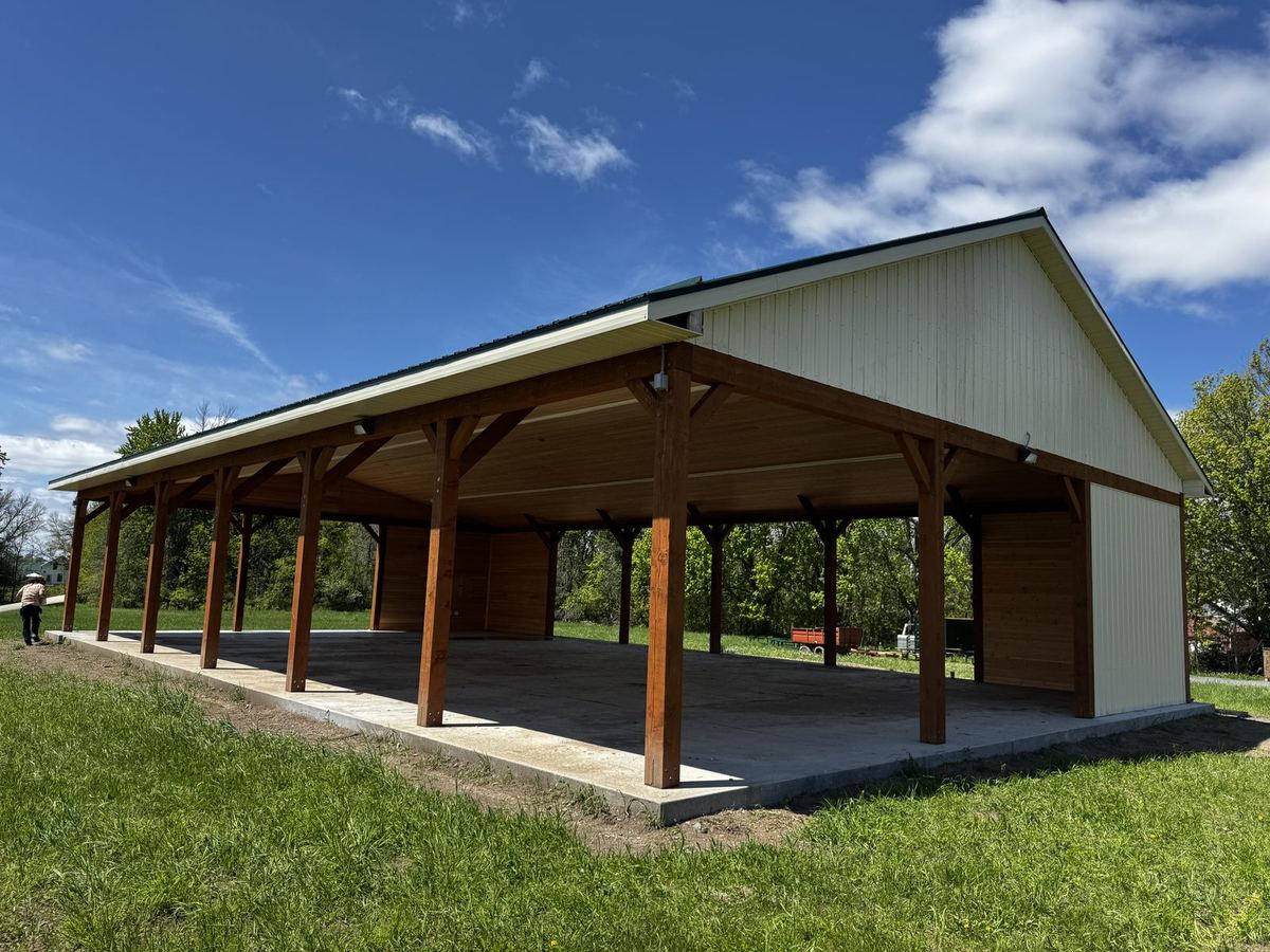 Open timber pavilion with stained posts and beams on a rural property